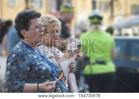 Garda Itali - May 182015: Two corpulent ladies talk holding huge portions of the ice cream corresponding to their proportions in hand.