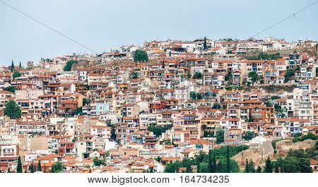 Aerial panoramic view of the colorful Thessaloniki city. Houses with red tile roofs are arranged in rows on a hill. Greece