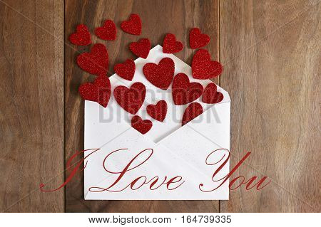 Valentine's Day Love Letter Spilling Out Red Hearts Onto Wood Background