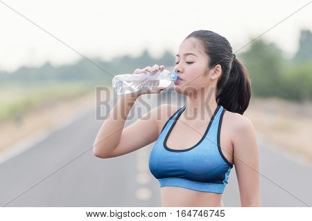 Female drinking a bottle of water on sunset. Sport makes the heart beat faster. Thirst by drinking water. Clean Drinking bottle Water. Heat need to drink bottle water.