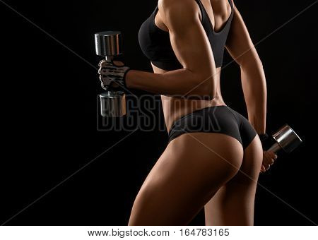 Backside to die for. Cropped closeup of perfectly shaped female buttocks of a fit and toned sportswoman with dumbbells in her hands