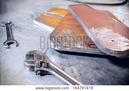 Adjustable and open-end wrenches. Steel metal plate stacked. Abstract industrial background.