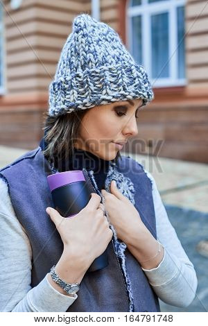 The girl with thermo cup, is walking through the old town