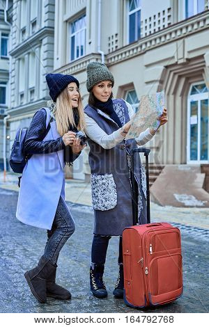 Two friends tourists choose attractions on the paper map