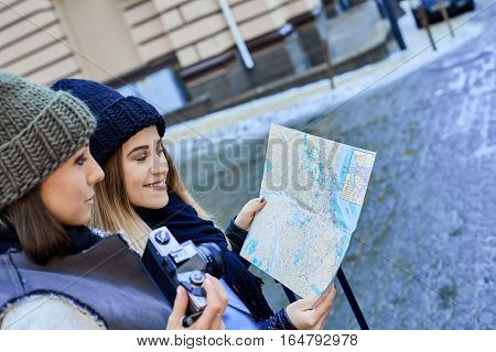 Two friends tourists choose attractions on the paper map