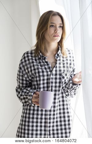 Melancholy girl having coffee looking out the window