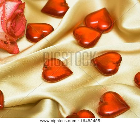 red rose on satin with hearts