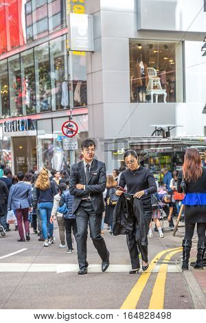 Hong Kong, China - December 6, 2016: couple of modern young colleague in uniform, man and woman, talking friendly in Causaway Bay, Jardine's Crescent street market.