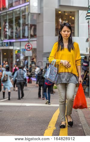 Hong Kong, China - December 6, 2016: asian nice young woman with shopping bags in street market Jardine's Crescent, Causaway Bay, shopping district, full of roadside famous brand shops.