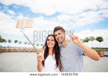 Smiling Attractive Man And Woman Making Selfie On Monopod