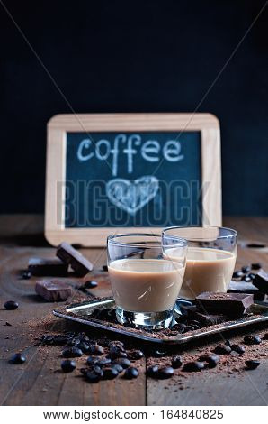 Shot glasses with homemade baileys roasted coffee beans and chocolate chalk board heart drawing love selective focus toned image