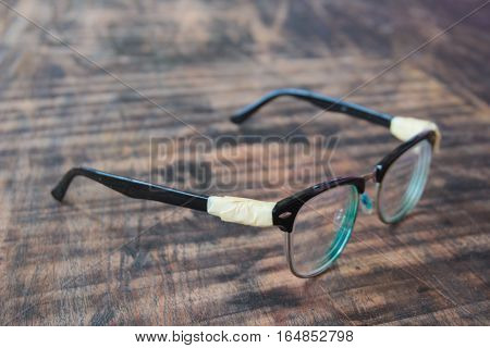 The old glasses legs are wrapped with masking tape is placed on the table.