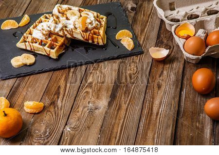 Two Belgian waffles with eggs on wooden table