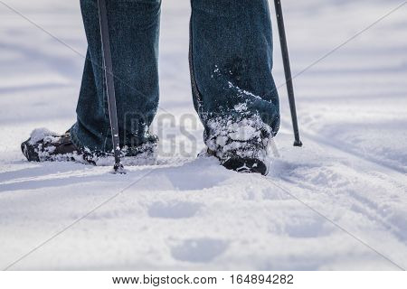 Closeup of person walking in snow with poles and one boot pointed