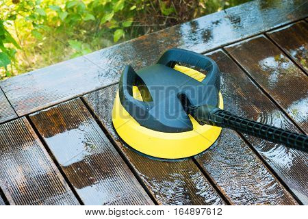 cleaning terrace with a power washer - high water pressure cleaner on wooden terrace surface