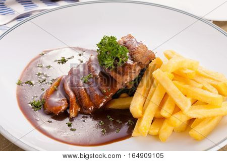 A nice dish of roasted duck breast confit in orange sauce served with fries on the table