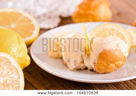 Lemon Profiteroles with custard cream on white dish.