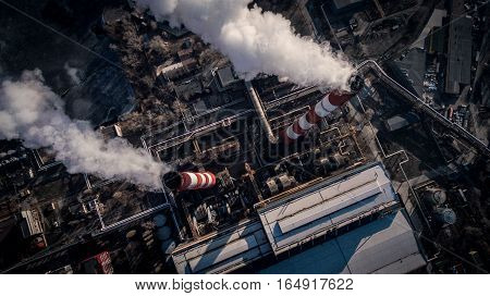Air pollution by smoke coming out of two factory chimneys. Industrial zone in the city. Kiev, Ukraine, aerial view