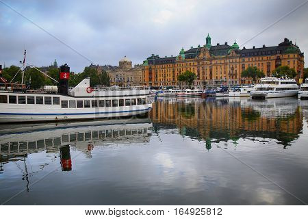 STOCKHOLM SWEDEN - AUGUST 20 2016: Many people walk and visit on Strandvagen street on Ostermalm distric with touristic sightseeing boats in Stockholm Sweden on August 20 2016.
