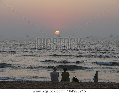 people watch the sunset into the ocean