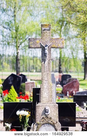 Concrete old cross with crucifix in cemetery in summer.