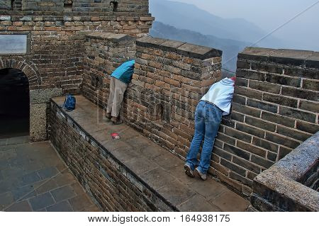 The Great Wall of China in early spring; one of a series of pictures. This image has been enhanced with a HRD filter to make the details and colors pop. The image shows two women leaning out over a parapet looking down below.