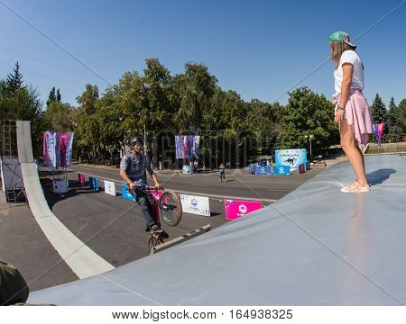KAZAKHSTAN ALMATY - AUGUST 28, 2016: Urban extreme competition, where the city athletes compete in the disciplines: skateboard, roller skates, BMX. Bmx stunt performed at the top of a mini ramp on a skatepark