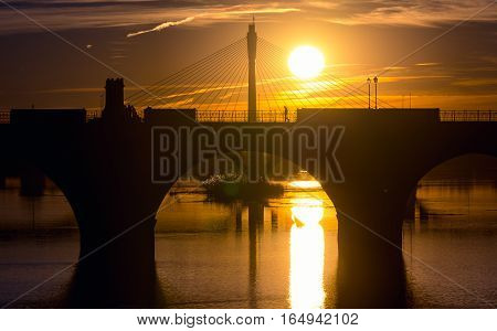 backlighting palms bridge and Guadianas River in sunlate