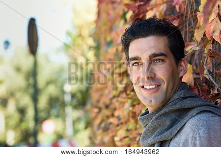 Man Wearing Winter Clothes Smiling In Autumn Leaves Background