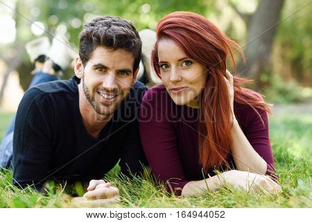 Beautiful Young Couple Laying On Grass In An Urban Park.