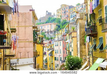 Riomaggiore village La Spezia province Liguria northern Italy. View of the colourful houses on steep hills the castle with clock laundry on balconies. Part of the Cinque Terre National Park and a UNESCO World Heritage Site.