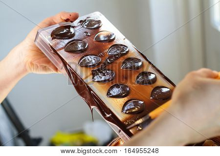 Cholocate mold held by hand and filled with chocolate