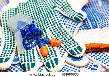 Thin work gloves with green pimples and ear plugs close up Personal protective equipment background. Industrial safety concept.