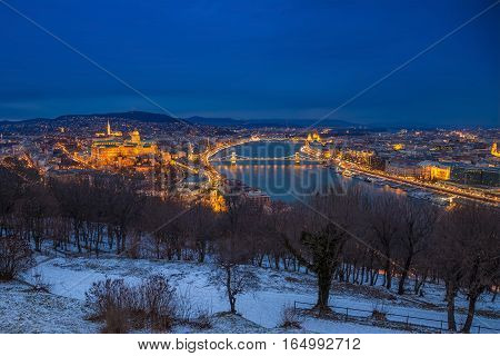 Budapest Hungary - Panoramic skyline view of the Buda Castle (Royal Palace) Chain Bridge Danube River and the Parliament at blue hour as seen from Gellert Hill in winter time