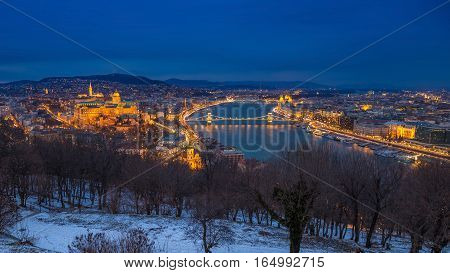 Budapest Hungary - Panoramic skyline view of the Buda Castle (Royal Palace) Chain Bridge Danube River and the Parliament at blue hour as seen from Gellert Hill in winter time
