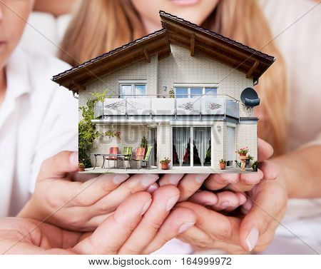 Close-up Of Family Holding The House Model Together