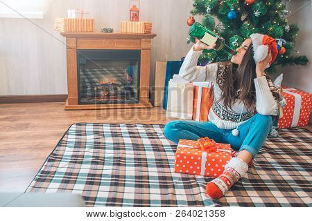 Young Woman Srinks Alcohol From Green Bottle. She Sits On Floor And Holds Head With Hand. There Is R