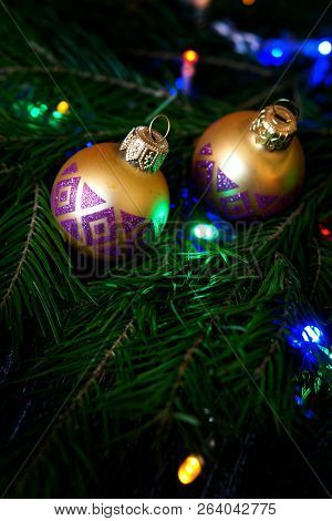 Shiny Balls On A Christmas Tree Among Colorful Lights. Congratulations On The New Year And Christmas