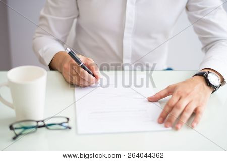Close-up Of Unrecognizable Man Signing Contract In Office. Businessman In White Shirt Concluding Dea