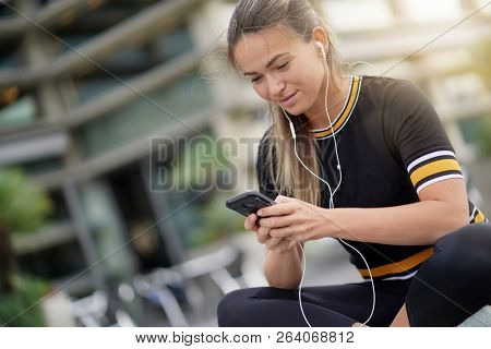 A sudent sitting outdoors looking at her cellphone 