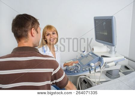 The Lady Ultrasunography Doctor Is Explaining To The Patientat Divice, In Medical Office