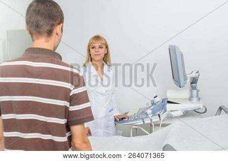 The Lady Ultrasunography Doctor Is Explaining To The Patientat Divice, In Medical Office
