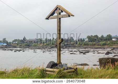 Orthodox Wooden Cross And Church With Houses On Background At Low Tide