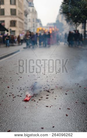 Red Firecrackers Exploding With Smoke On The Asphalt With Peolple In The Background For The Chinese 