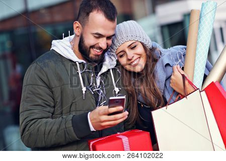 Portrait of happy couple with shopping bags after shopping in city
