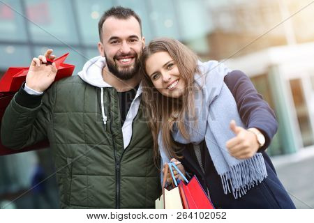 Portrait of happy couple with shopping bags after shopping in city