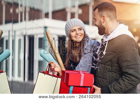 Portrait of happy couple with shopping bags after shopping in city