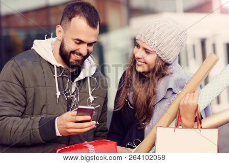 Portrait of happy couple with shopping bags after shopping in city
