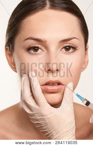Lip Augmentation Injection. Young Woman. Doctor Hand. Medical Process