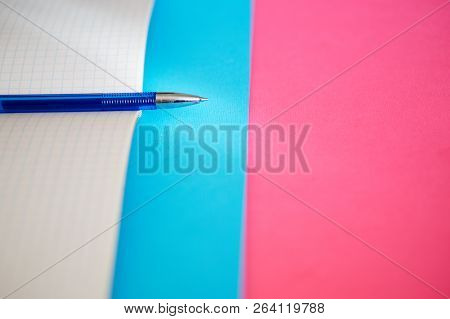 Time For Business And Study. The Pen Lies On A Notebook For Mathematics On A Blue And Pink Backgroun